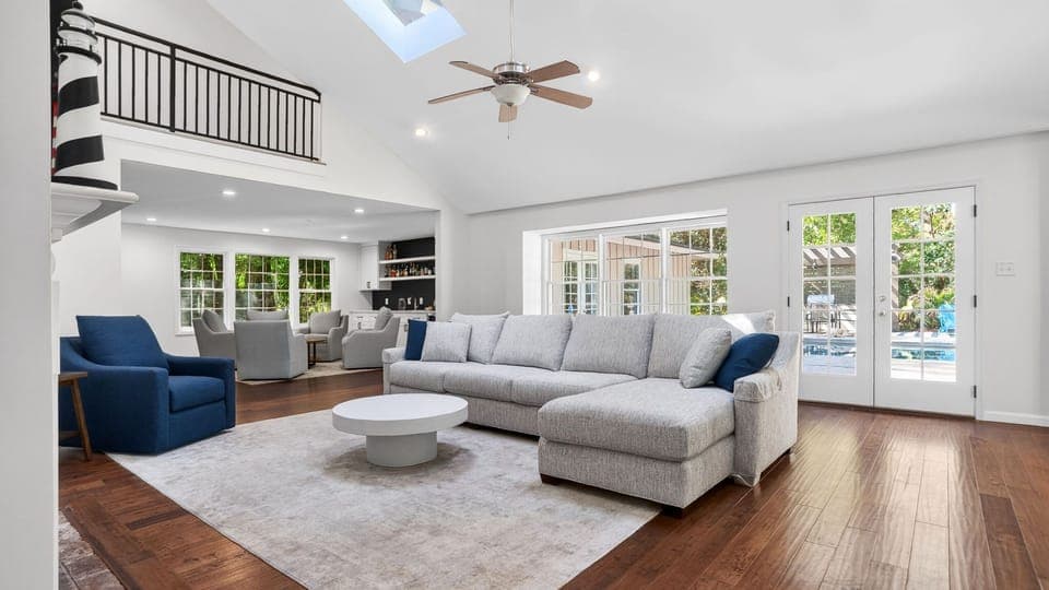 Airy modern living room with soft neutrals, vaulted ceilings, and French doors opening to a poolside retreat.
