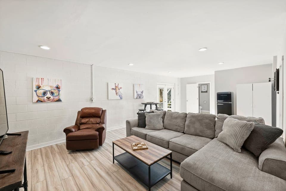 Lower level game room with couch, chair, tv, darts &amp; high top bar table.