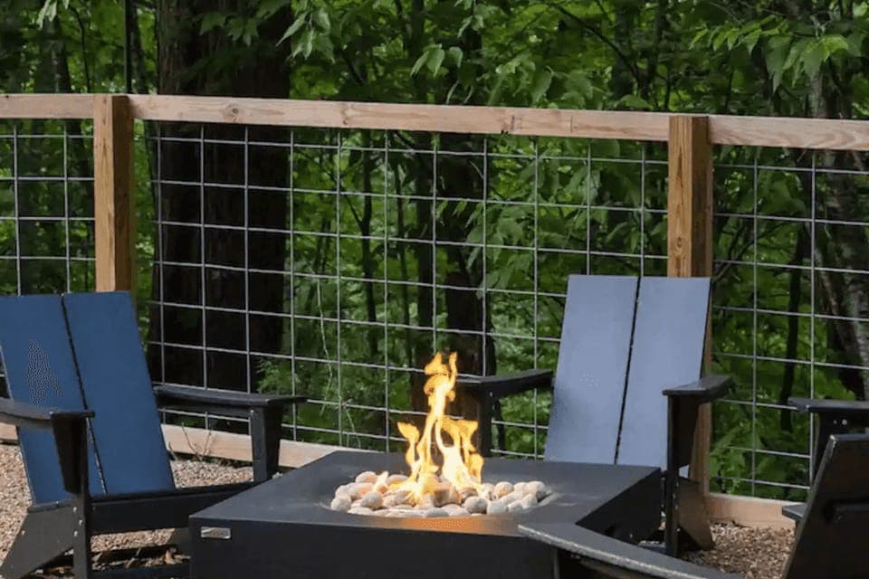 Shared outdoor fire pit lounge surrounded by forest greenery.