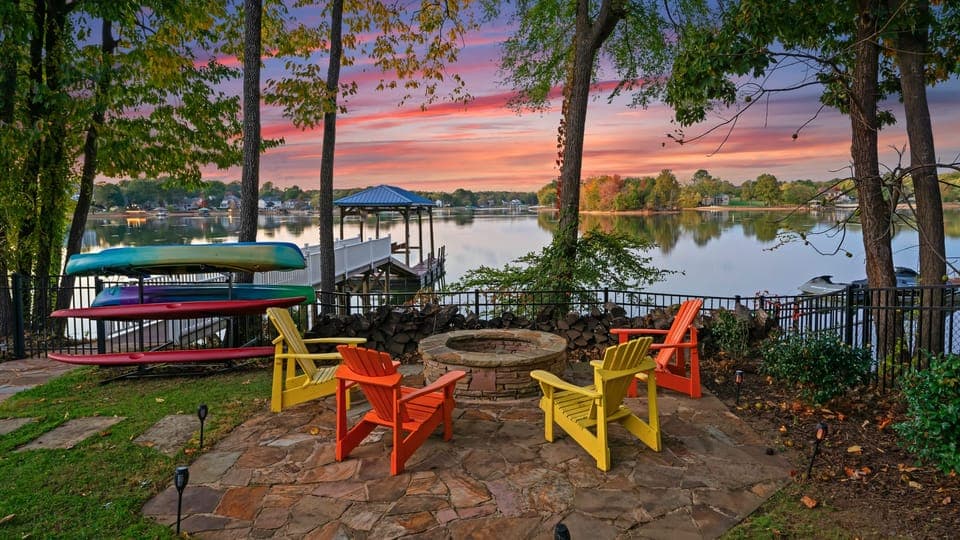 Outdoor firepit with colorful chairs overlooking the lake at sunset.