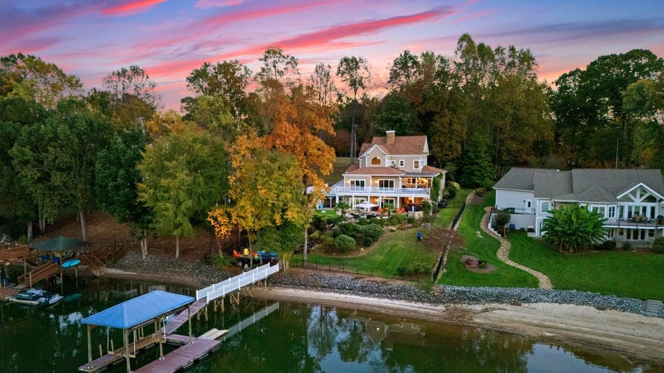 Aerial view of lakeside property with dock and boathouse.