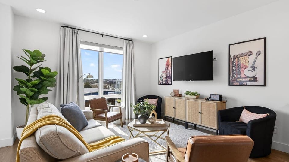 A bright, inviting living area with a queen sleeper sofa and large windows that bring in natural light.