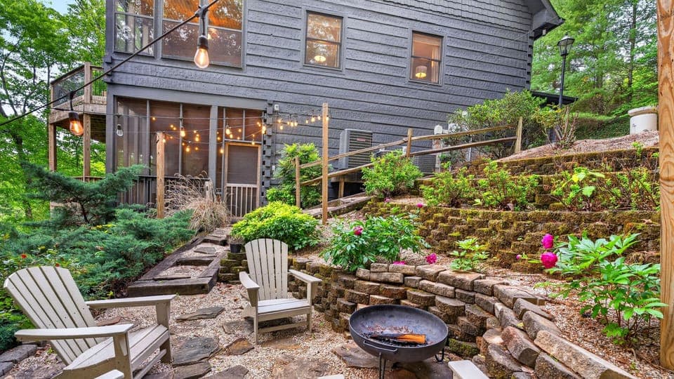 Charming backyard retreat with fire pit, string lights, and tiered garden seating for cozy evenings outdoors.