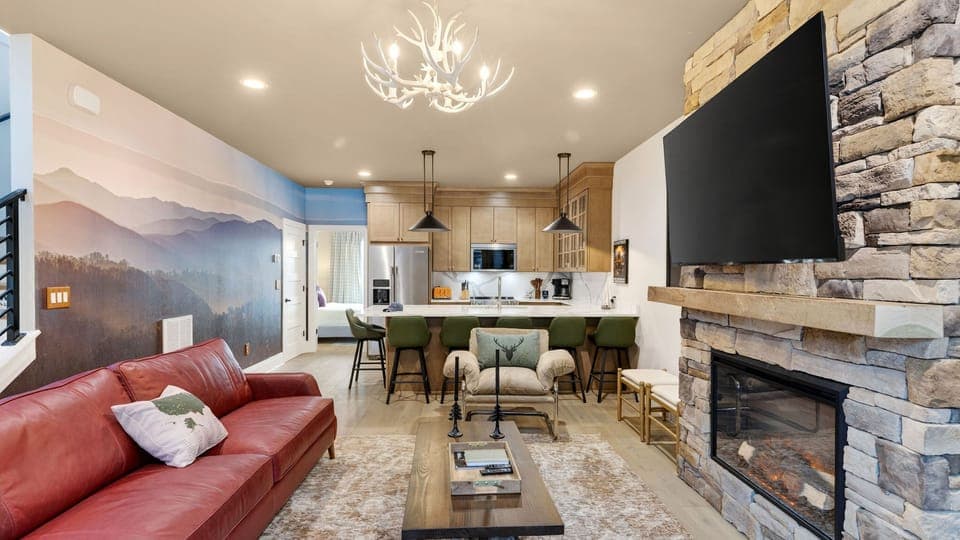 Gather by the stone fireplace—huge TV, cozy seating, and a warm lodge-style vibe. (The Lodge)