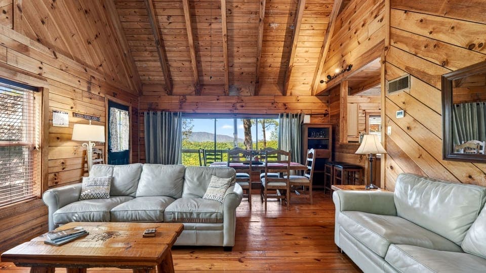 Warm wood interiors and an open-concept living space set the tone, with large windows framing peaceful mountain views just beyond the dining area. (Elijah's Cabin)