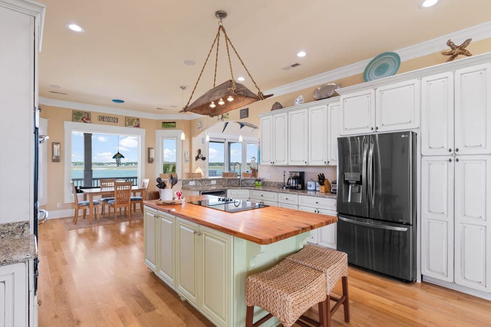 You'll love cooking in this spacious gourmet kitchen with warm wood counters, coastal charm, and stunning water views streaming through the windows.