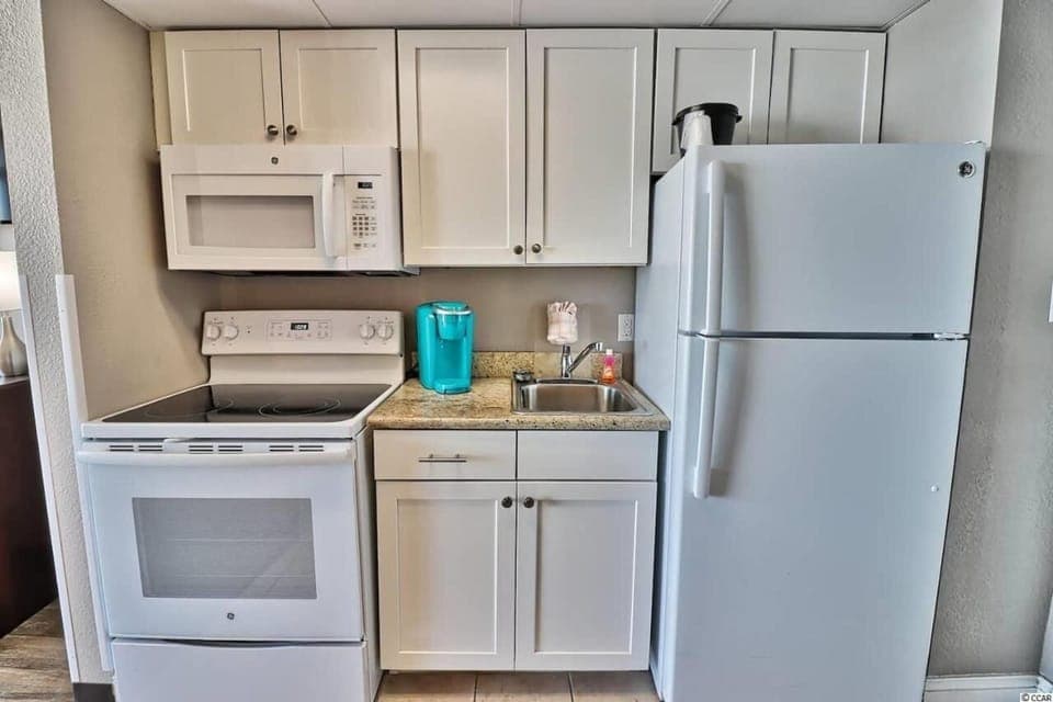 Compact yet fully equipped kitchen with fridge, microwave, and coffee maker