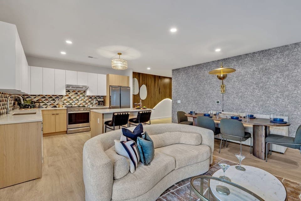 Bright open living space featuring smart flat-screen TV, designer furnishings, and access to a large corner private balcony.