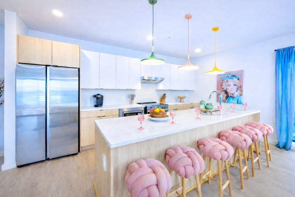 Fully equipped kitchen stocked with all culinary essentials and featuring brand-new stainless-steel appliances and a large kitchen island offering bar seating.
