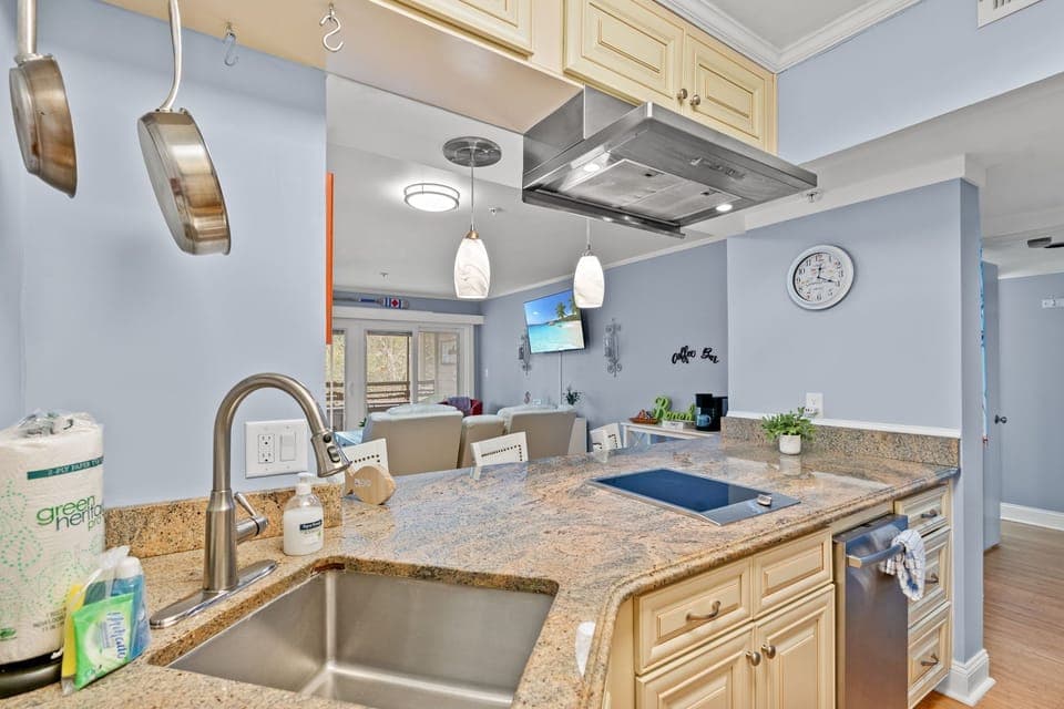 Granite kitchen with island seating, induction cooktop, and open living view