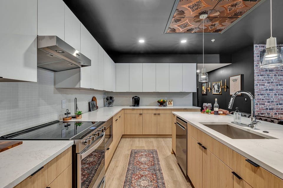 The fully equipped modern kitchen features culinary essentials, stainless steel appliances, and island bar seating.