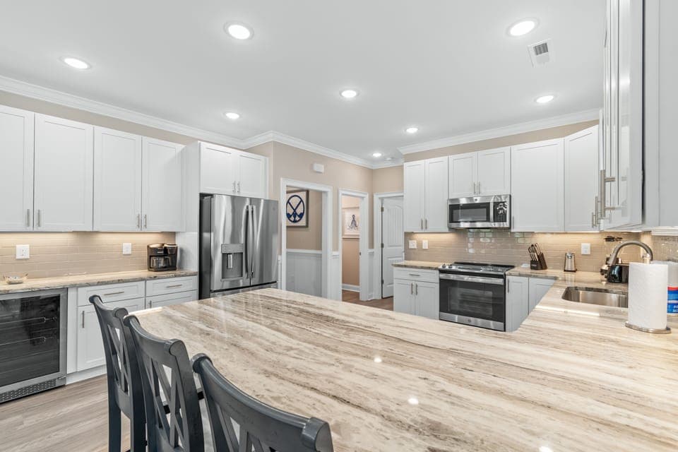 Your gourmet kitchen features pristine white cabinets, gleaming granite counters, and premium stainless appliances—perfect for creating memorable meals during your stay.
