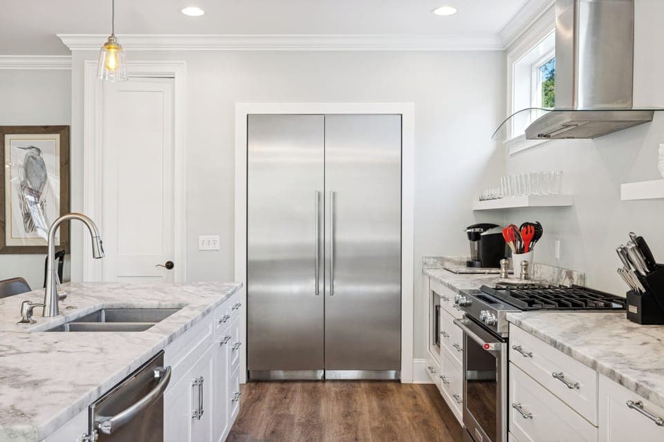 A fully stocked kitchen with stainless steel appliances, and 4 barstools for extra seating.