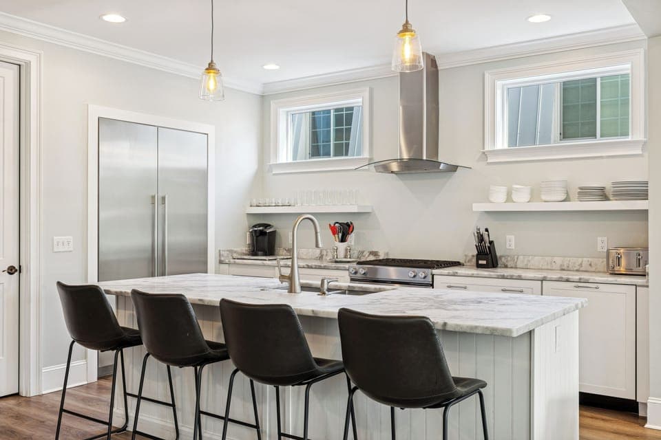 A fully stocked kitchen with stainless steel appliances, and 4 barstools for extra seating.