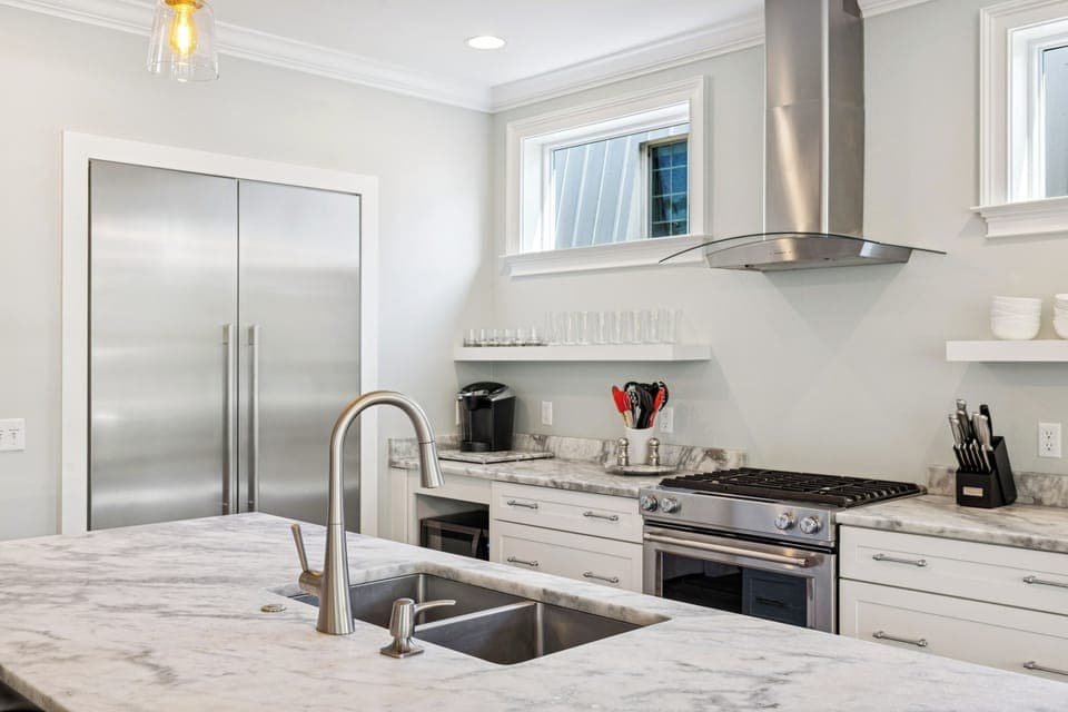 A fully stocked kitchen with stainless steel appliances, and 4 barstools for extra seating.