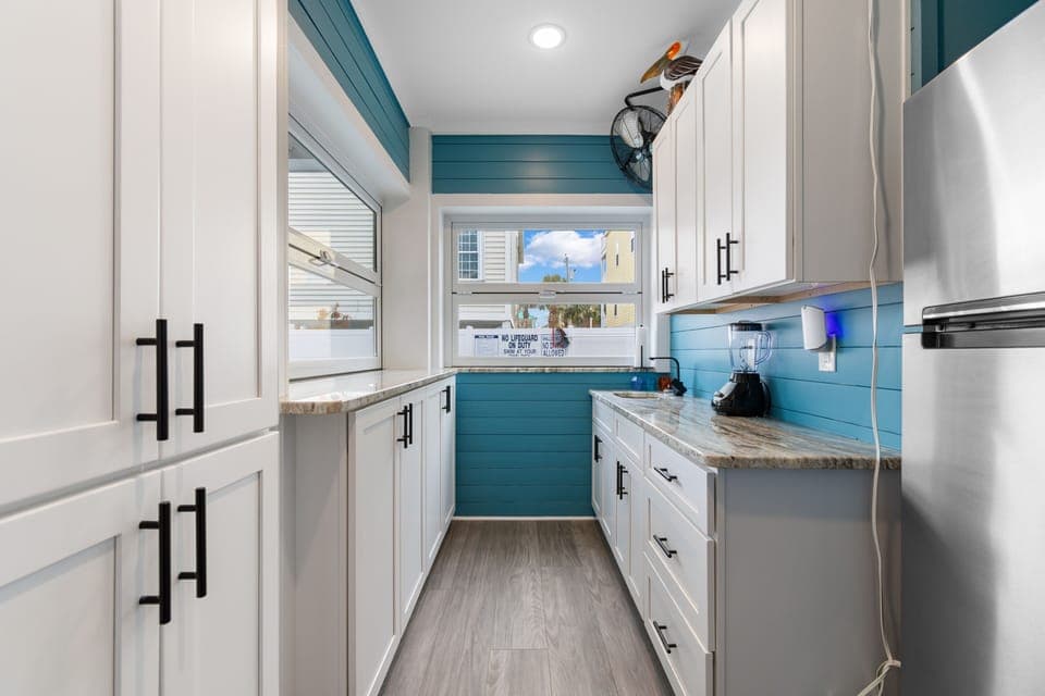 Your fully equipped outdoor kitchen/bar features vibrant teal accents and modern appliances, making meal prep a joy with granite countertops and ample storage space.