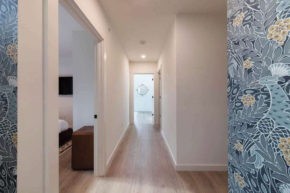 Vibrant and inviting hallway with a bold blue bird accent wall, creating a vibrant and welcoming transition to the living spaces.
