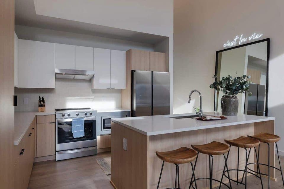 Stylish and functional tall ceiling kitchen with stainless steel appliances, full size mirror and natural wood accents.