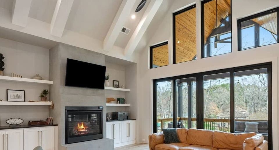 Sunlit haven with soaring ceilings, plentiful natural light, 55` LG WebOs TV, and a warm fireplace, perfect for relaxing evenings!