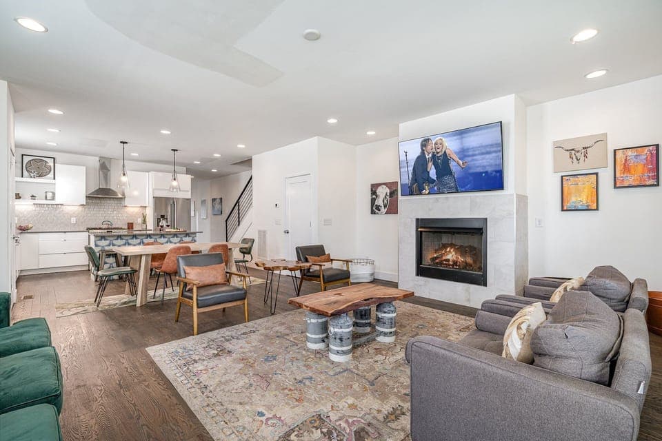 Unit 2: Welcoming living area with a vibrant green accent wall, large smart TV, fireplace, and plush seating arranged to take in the serene outside views.