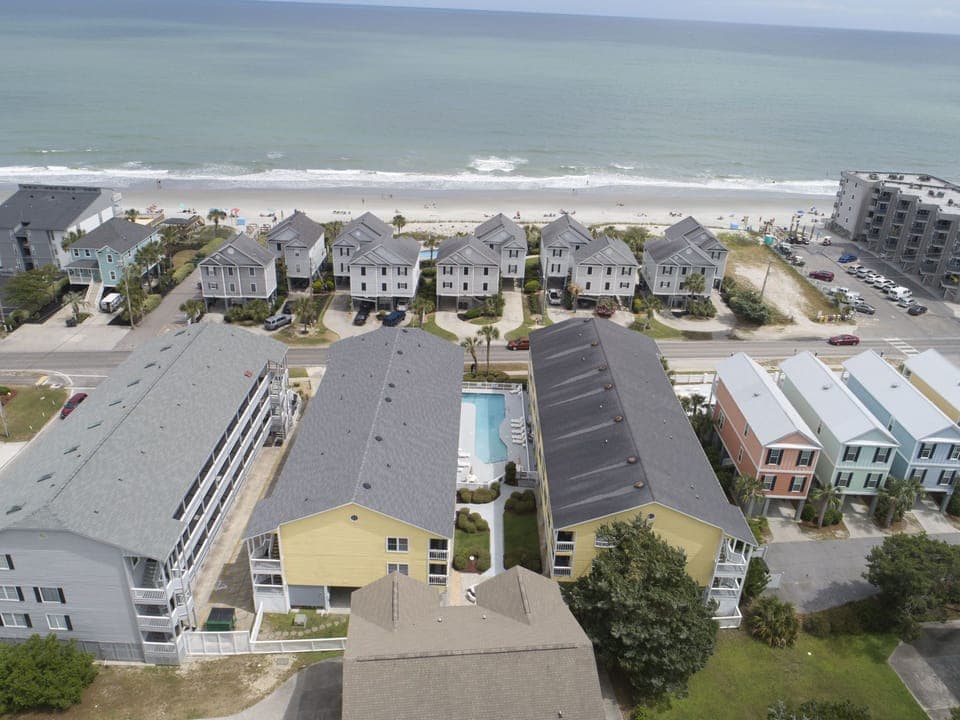 This aerial view of Sandy Shores III highlights its prime beachfront location, outdoor pool, and easy access to nearby attractions in picturesque Murrells Inlet, SC.