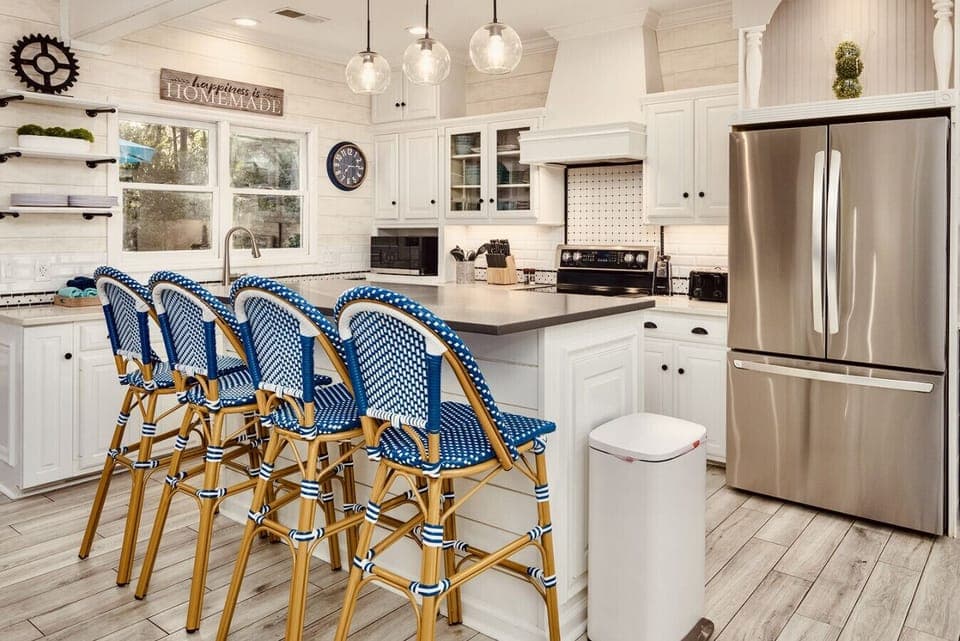 The bright and spacious kitchen has plenty of prep and serving space between the quartz countertops around the perimeter of the kitchen and those on the large island with four French bistro stools.