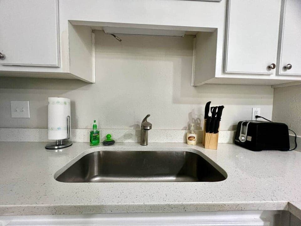 This fully equipped kitchen features stainless steel appliances, a large counter with seating, and a cozy dining nook framed by natural light. Whether you’re cooking a full meal or enjoying takeout, this space is perfect for gathering and dining in.