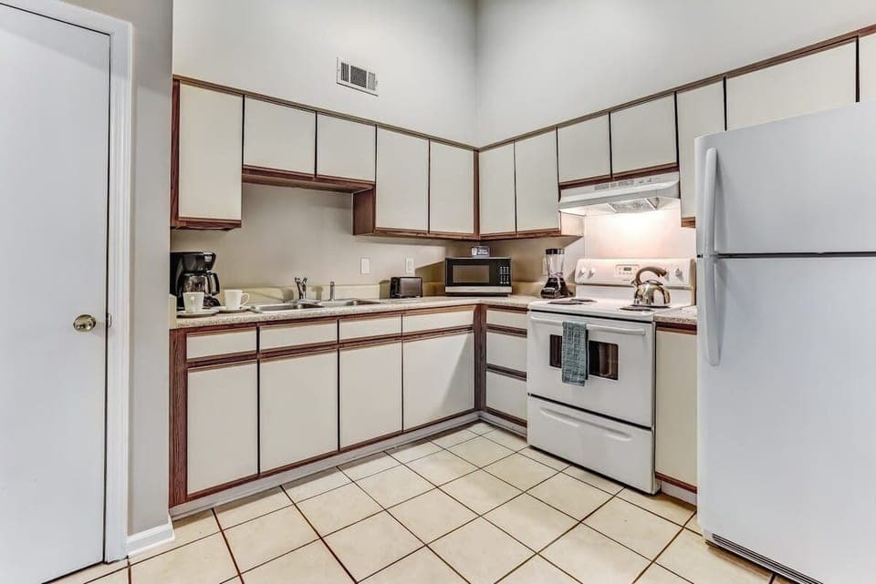 Full view of the well-equipped kitchen with white cabinets and tile flooring.