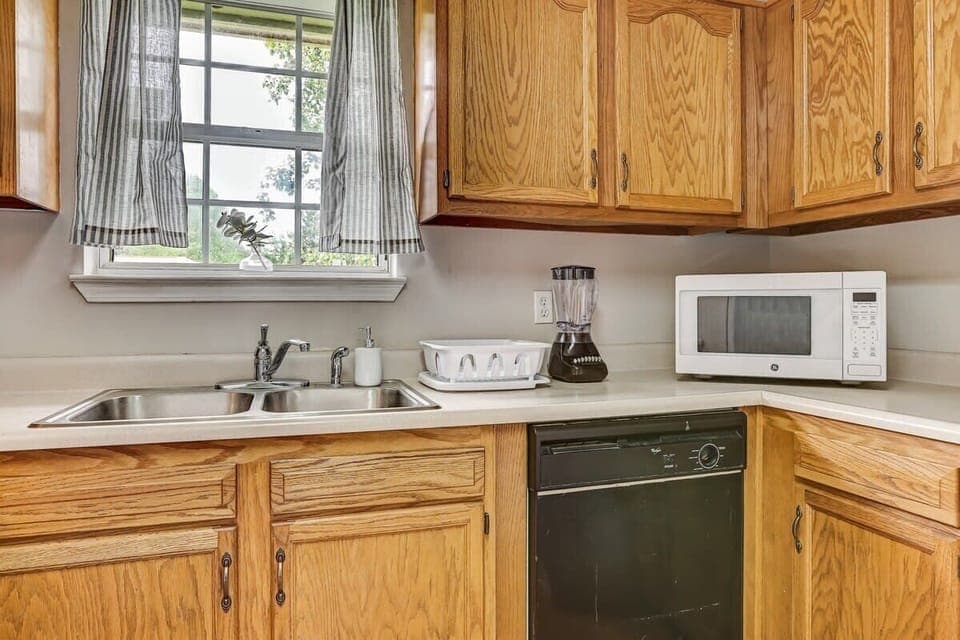 Kitchen counter area with sink, microwave, and small appliances for added convenience.