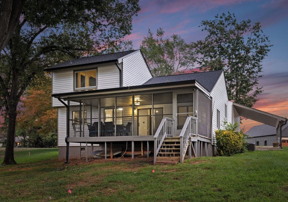 Charming exterior with a screened-in porch, set against a vibrant sunset sky.