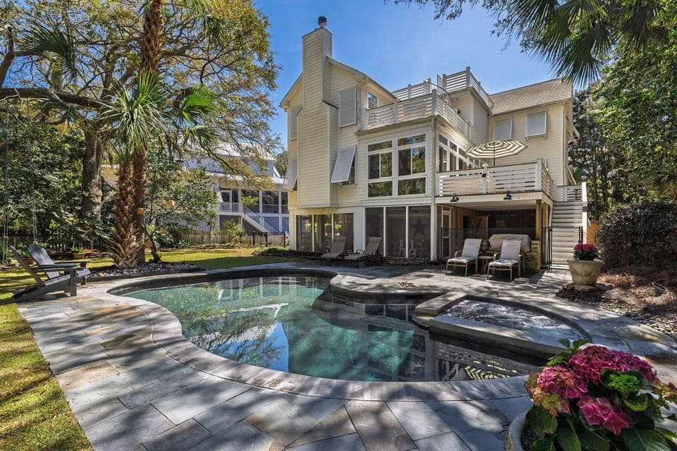 Luxurious waterfront home featuring pool, spa, and lush tropical landscaping in an upscale neighborhood setting.