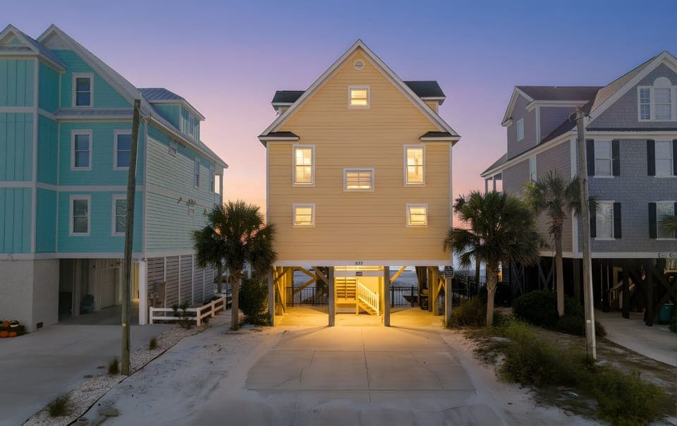 Charming beachside home with colorful coastal neighbors creates perfect vacation atmosphere at twilight.