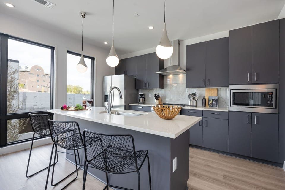 Unit 1: Fully equipped kitchen with stainless steel appliances, basic cooking essentials, toaster, coffee machine, and kitchen island seating.