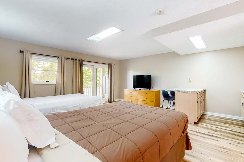 Spacious studio suite with 2 beds, TV, and kitchenette. Perfect for families, groups, and extended stays. Bright, clean studio lodging with mini kitchen, dining space, and balcony access.