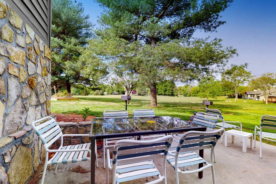 Shared outdoor patio dining with table seating and open lawn views. Ideal for group meals, BBQs, and relaxing. Outdoor space, shared grounds, picnic vibes, and peaceful green setting.