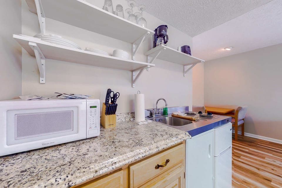 Kitchenette with counter space, sink, cooktop, microwave, coffee maker, dishes, and utensils/. Perfect for quick meals and long stays. Clean, convenient studio for couples, and families.