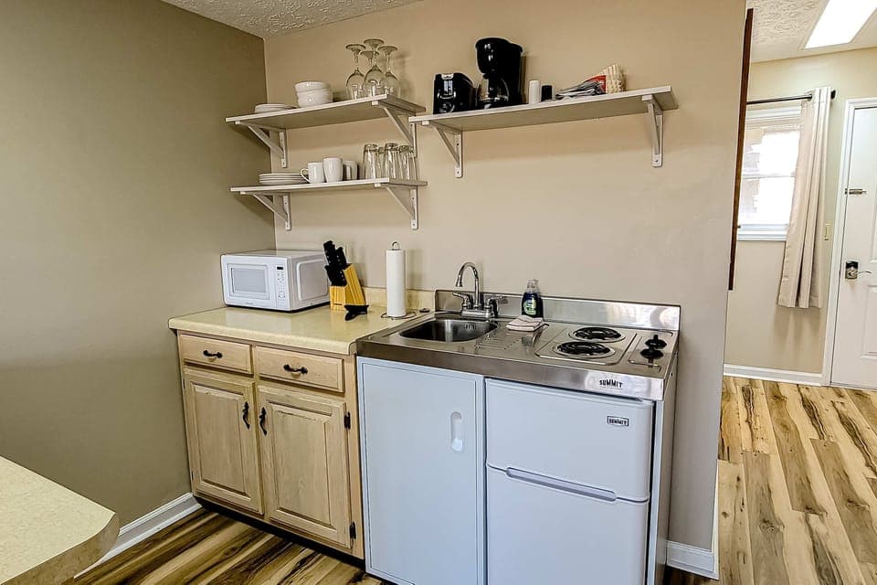 Convenient kitchenette with sink, microwave, mini-fridge, coffee maker & 2-burner cooktop. Stocked extended-stay, self-catering, budget-friendly, long-term essentials.