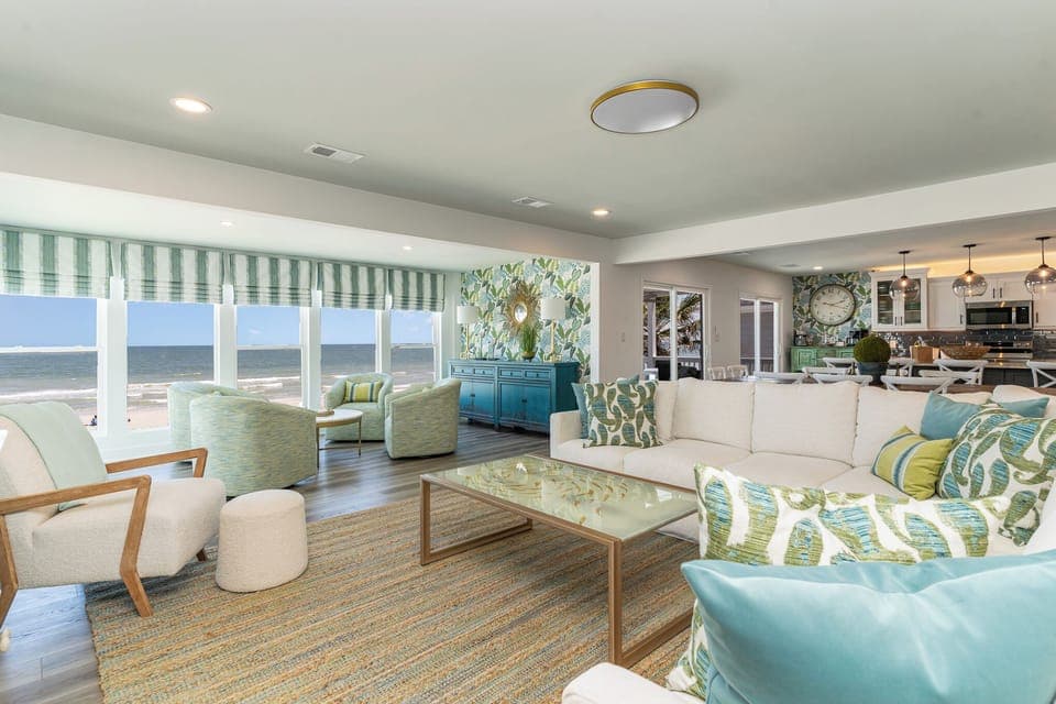 Sink into plush coastal furnishings while enjoying stunning sea views through floor-to-ceiling windows in this bright, elegantly designed living space.