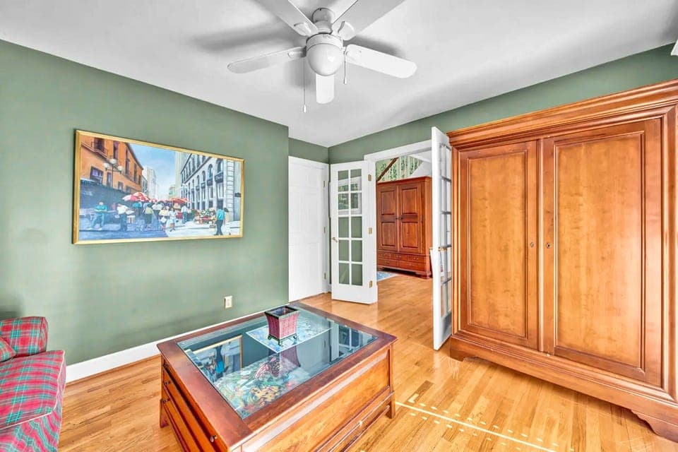 Relax in this charming room with sage-green walls, gleaming hardwood floors, and classic furnishings that create a welcoming atmosphere.
