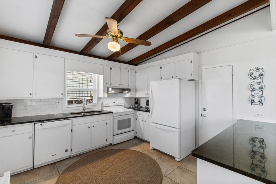 Cook your favorite meals in this fully-equipped kitchen featuring exposed wooden beams, white appliances, and ample counter space for your culinary adventures.
