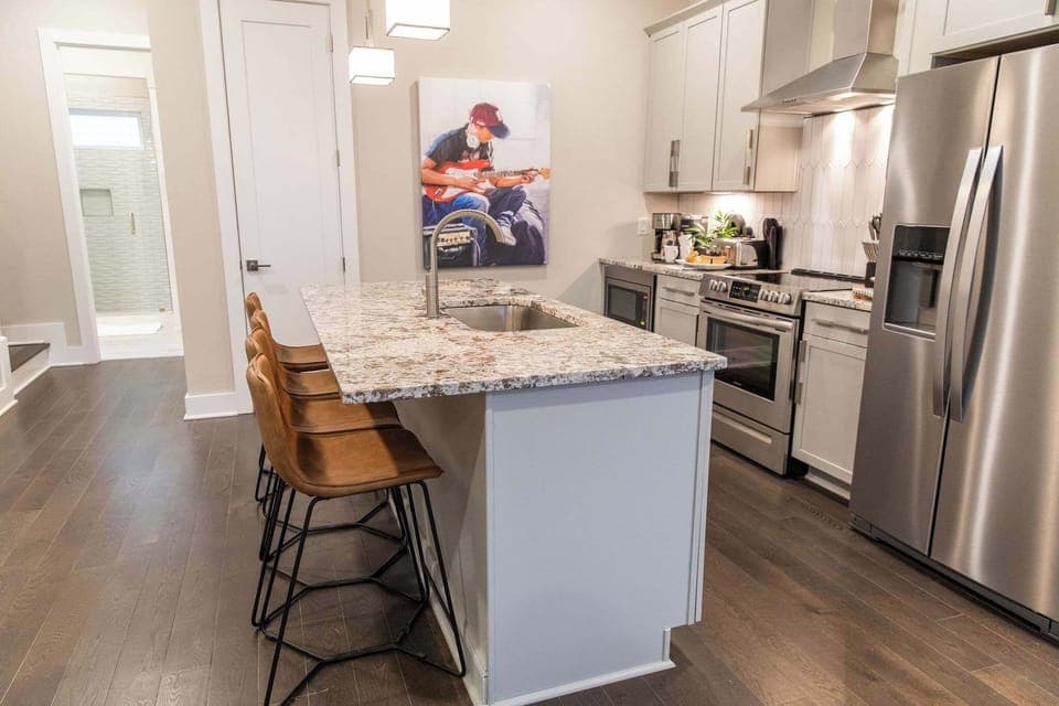 Sleek, modern kitchen with granite island and guitar-inspired art.