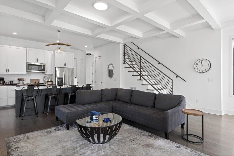 Living room view highlighting the sleek black metal staircase and open floor plan