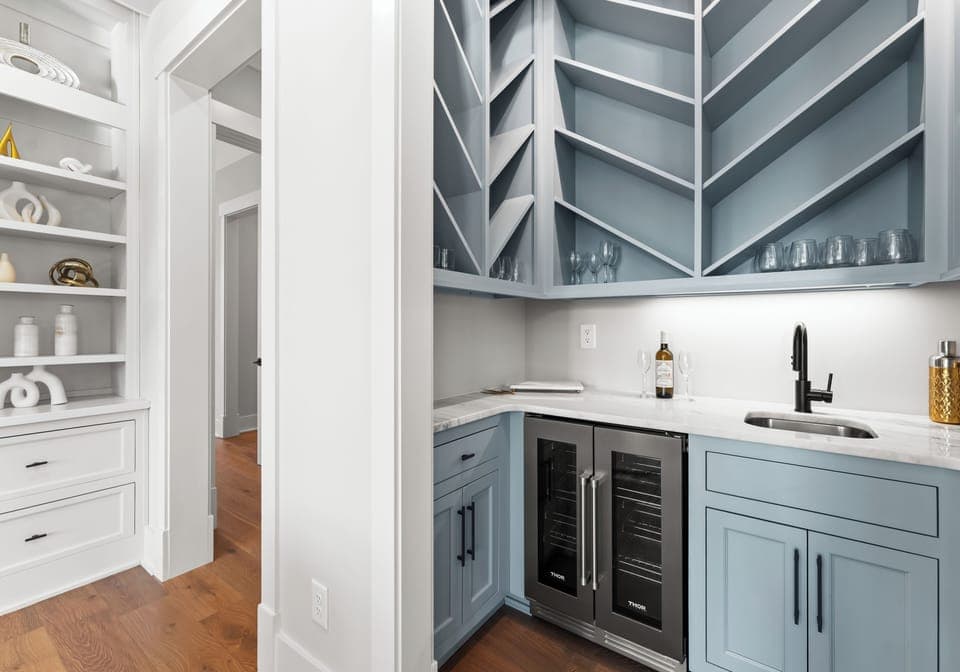 Close-up of a built-in wet bar with a wine cooler and light blue cabinetry.