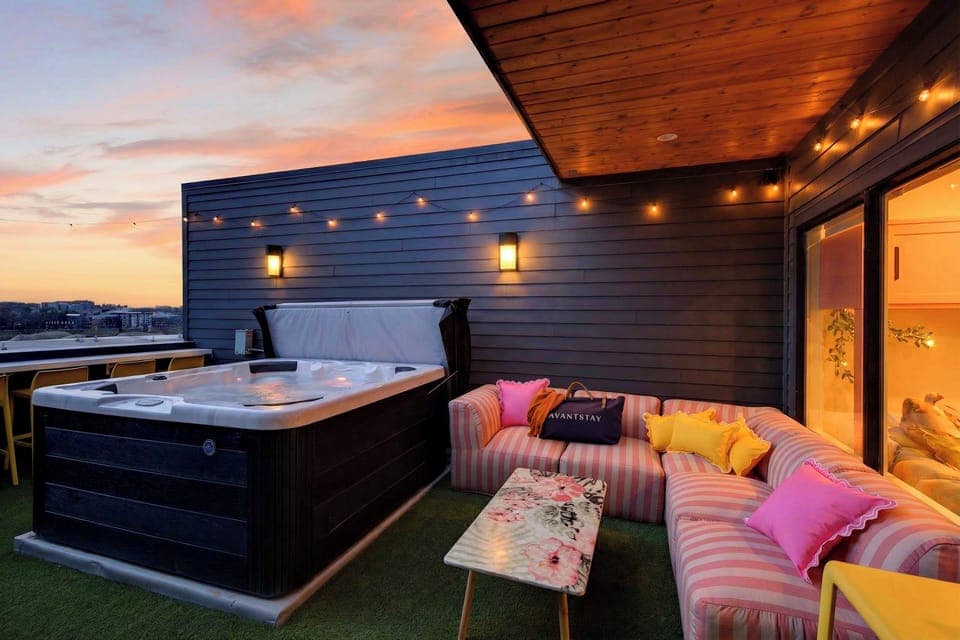 Rooftop hot tub with skyline views, string lights, and sunset vibes.
