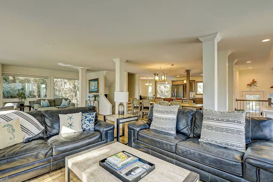 Sink into spacious leather seating with decorative pillows as natural light fills your open-concept living space, perfect for relaxing after exploring.