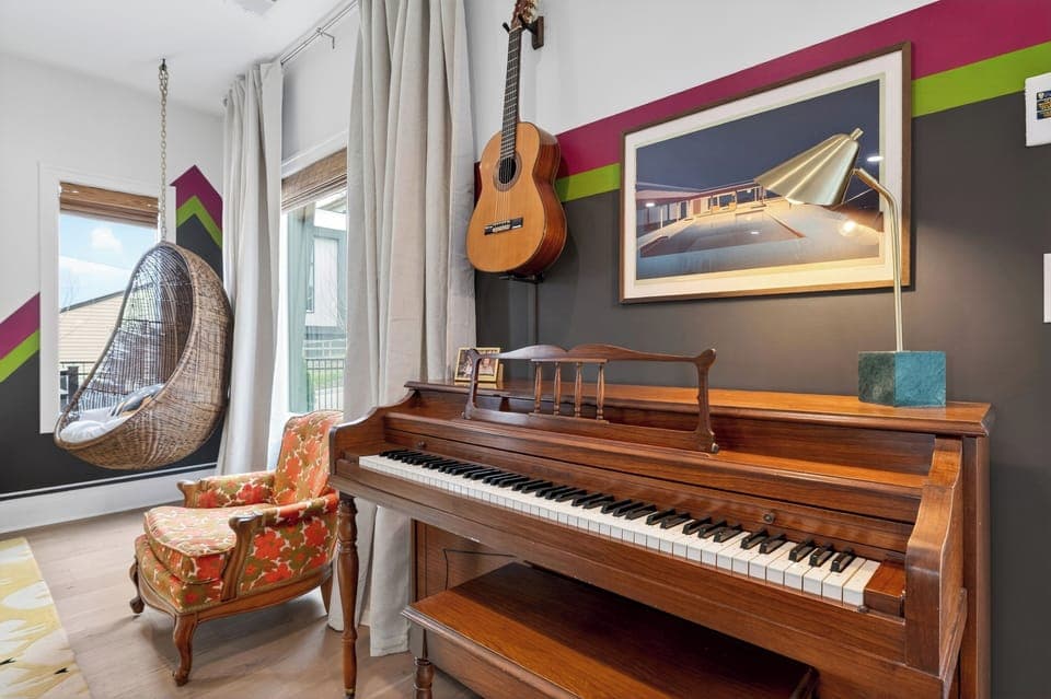 Music-inspired corner with a piano, guitar, custom guitar speakers with great sound system, and a cozy hanging chair that adds personality to the space. (That ’70s Show)