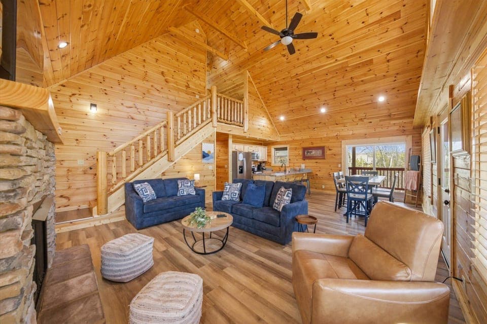 Your cozy cabin retreat features warm wood throughout, with plush seating and a stone fireplace creating the perfect mountain getaway atmosphere.