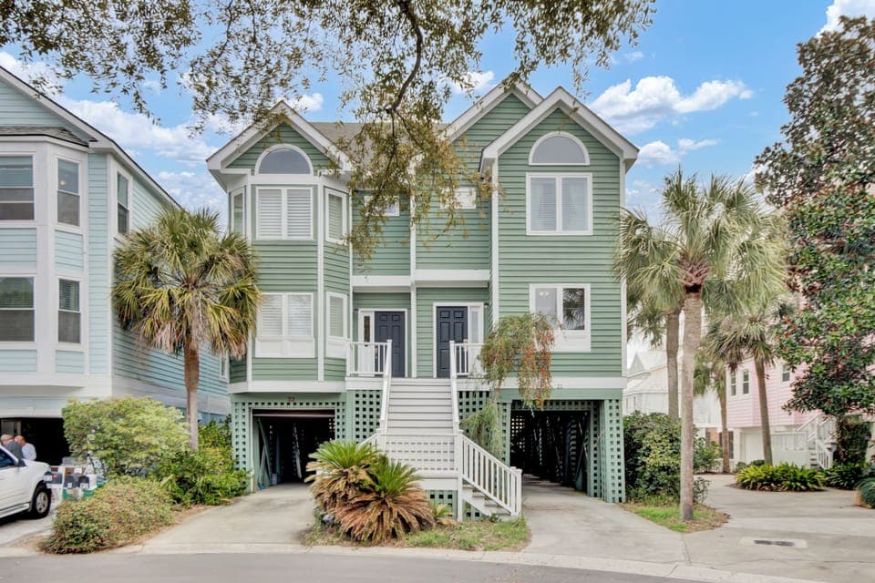 Coastal-style home with elevated design featuring tropical landscaping and convenient parking beneath the property.