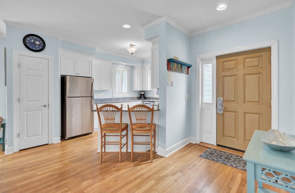 Your charming open kitchen invites morning coffee at the breakfast bar, with gleaming appliances and coastal blue walls creating a welcoming space.