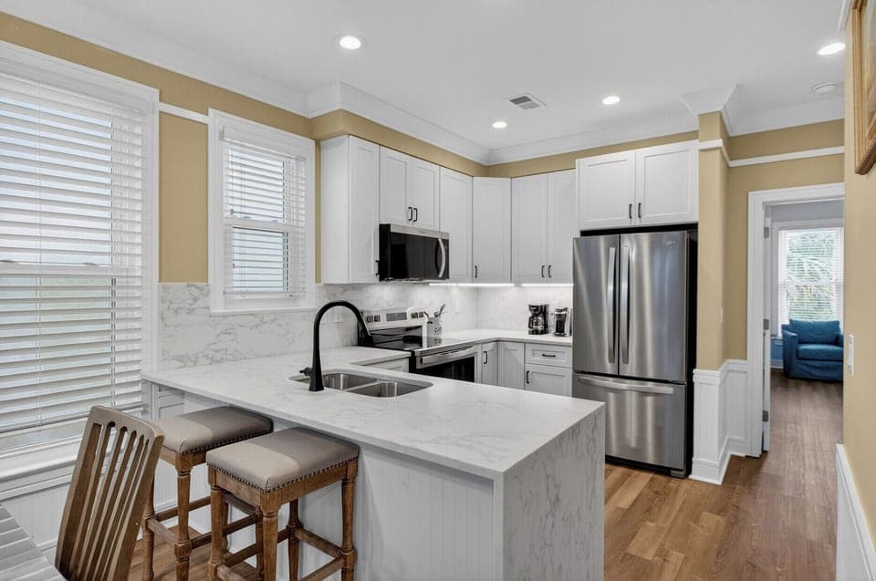 Your modern kitchen features pristine white cabinets, marble countertops, and stainless steel appliances, creating the perfect space for culinary adventures.